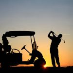 A silhouette of a senior male Caucasian golfer at sunset with powercart. Golfer is demonstrating great form and balance as he swings into a finish position. Image can be used for teaching, golf academy, lessons, senior, retirement, golf resort, golf vacation, back view, athlete, leisure, sports, weekend activities, unrecognizable people, swinging, instruction, and golf cart communities.